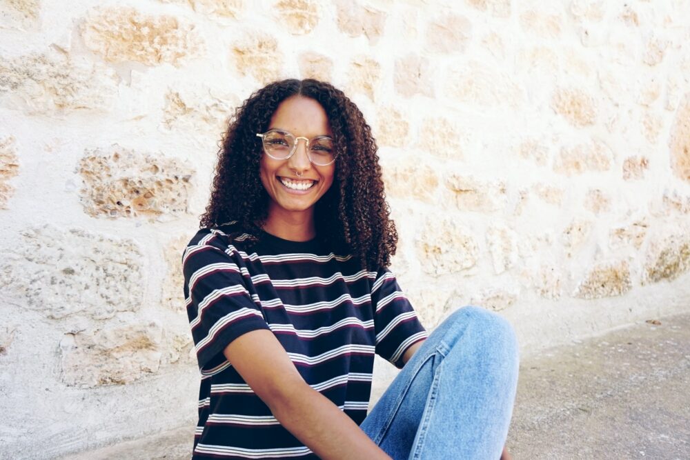 A portrait of happy smiling young black woman wearing glasses, j